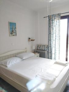 a bedroom with a white bed with a window at Rebekka's Guest House Elani in Siviri