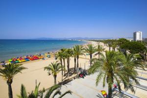 a view of a beach with palm trees and the ocean at GLAM ONLY FAMILIES Planet Costa Dorada in Salou