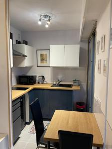 a kitchen with white cabinets and a wooden table at Grand Studio proche mer avec piscine. in Antibes