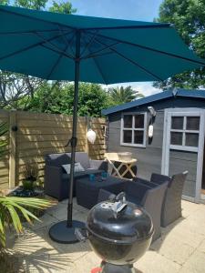 un grande ombrellone blu su un patio con griglia di Maison tout confort au calme à 300m de la mer et du GR34 avec jardin a Loctudy