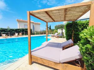 una piscina con una cama y una pérgola junto a una casa en Summer Villa Lagonissi en Lagonissi