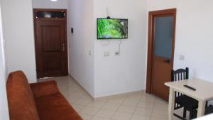 a living room with a couch and a tv on the wall at Deni's Family Apartment in New BLVD in Tirana