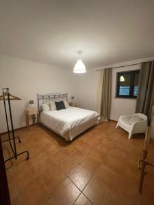 ein Schlafzimmer mit einem weißen Bett und einem Stuhl in der Unterkunft Casa Mimose Rosa in SantʼAngelo in Pontano