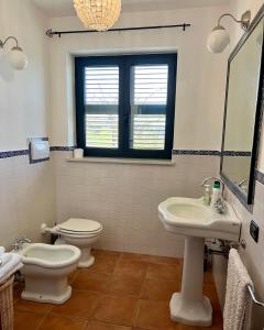 ein Badezimmer mit 2 WCs, einem Waschbecken und einem Spiegel in der Unterkunft Casa Mimose Rosa in SantʼAngelo in Pontano