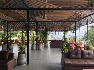 a patio with couches and tables and potted plants at Echo Hostel Koh Tao in Ko Tao