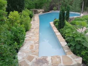 a swimming pool in a garden with a stone path around it at La Casita in Torres