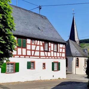 ein altes Haus mit grünen Rollläden und einer Kirche in der Unterkunft Ferienhaus Wagner in Bernkastel-Kues