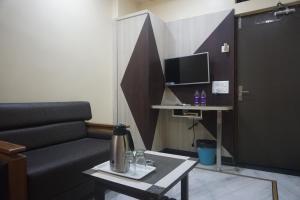 a living room with a couch and a table and a tv at Hotel Gujrat in Nagpur