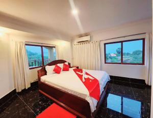 a bedroom with a bed with a red blanket and two windows at Kep Villa Hill Guest House 1 in Kep