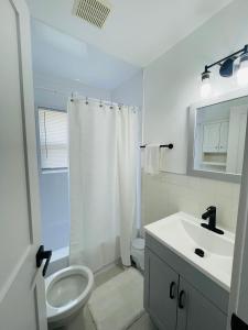 a white bathroom with a sink and a toilet at Newly renovated charming home with parking in Fort Washington