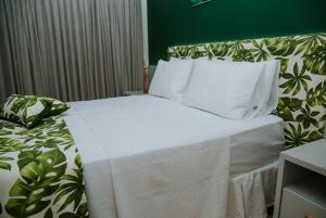 Bett mit weißer Bettwäsche und Kissen in einem Zimmer in der Unterkunft Resort Asenza Bangalô Barão 503 in Pitimbu