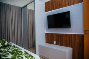 ein Schlafzimmer mit einem Flachbild-TV an der Wand in der Unterkunft Resort Asenza Bangalô Barão 503 in Pitimbu