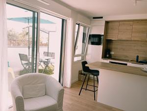 een woonkamer met een witte stoel en een keuken bij Arradon Golfe du Morbihan Appartement 2 Pièces plain-pied Terrasse in Arradon