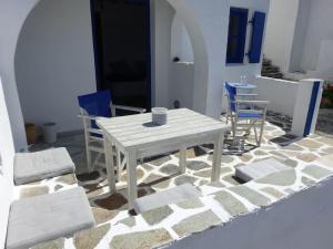 une table blanche et des chaises assises sur une terrasse dans l'établissement Studio Naxos Orkos plage, à Naxos Chora