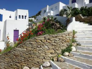 un mur en pierre avec des fleurs et des escaliers devant les bâtiments dans l'établissement Studio Naxos Orkos plage, à Naxos Chora