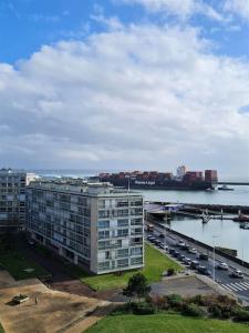een groot gebouw naast een rivier met een brug bij La Pause Marine in Le Havre