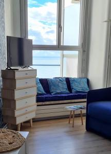 een woonkamer met een blauwe bank en een raam bij La Pause Marine in Le Havre
