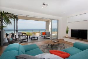 a living room with a blue couch and a television at Ocean At Seaford- Beachfront Luxury-Free Wifi in Seaford