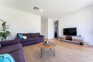 a living room with a purple couch and a tv at Ocean At Seaford- Beachfront Luxury-Free Wifi in Seaford