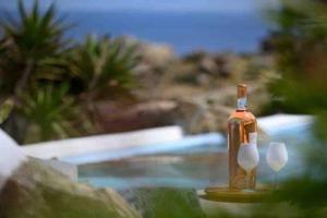 una bottiglia e due bicchieri da vino seduti accanto alla piscina di Paraga Scorpios area Villa2 by CalypsoSunsetVillas a Paradise Beach