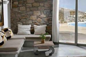 a living room with a couch and a stone wall at Paraga Scorpios area Villa2 by CalypsoSunsetVillas in Paradise Beach