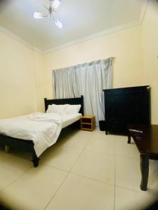 杜拜的住宿－Low-Priced Budget Rooms for rent near Dubai DAFZA，一间卧室配有一张床、一张桌子和一架钢琴