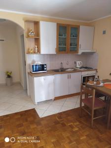 a kitchen with white cabinets and a table in it at Apartman Iva - Vantačići in Vantačići +2 photos
