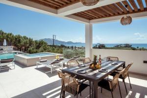a patio with a table and chairs and a swimming pool at Villa Roselia - Luxury Escape with Magnificent Views, by ZanteWize in Laganas
