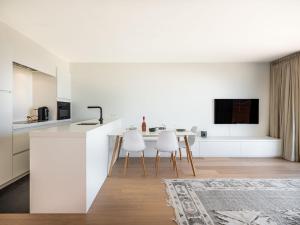 a white kitchen with a table and white chairs at Zilverzand 202 new construction located on the beach in Koksijde
