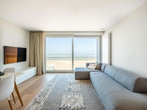a living room with a couch and a large window at Zilverzand 202 new construction located on the beach in Koksijde
