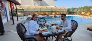 a man and woman sitting at a table by a pool at California Apart Otel in Oludeniz