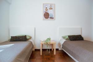 two beds in a room with a table and a picture at Cozy Room in Cascais City with Full Kitchen 5 minutes from the beach in Cascais