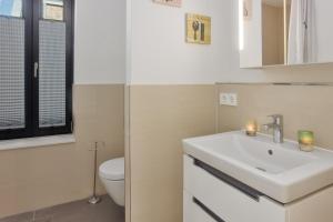 a white bathroom with a sink and a toilet at Jakobskoje in Heiligenhafen