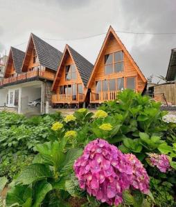 CALLA HOMESTAY DIENG في Diyeng: منزل خشبي أمامه زهور
