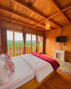 Un dormitorio con una cama grande con una ventana grande. en CALLA HOMESTAY DIENG, en Diyeng