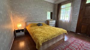 um quarto com uma cama com um cobertor amarelo em Green bunny guesthouse em Martvili