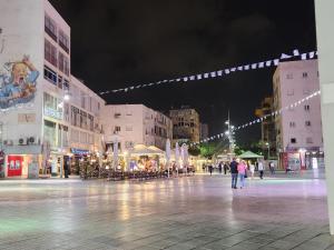 una plaza de la ciudad por la noche con gente caminando alrededor en Chilling in Netanya en Netanya