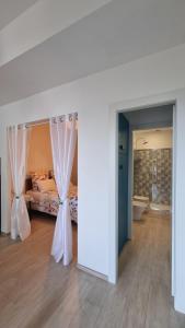 Alba di luna في سانتا تيريزا دي ريفا: غرفة نوم بسرير مع ستائر وحوض استحمام