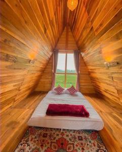 CALLA HOMESTAY DIENG في Diyeng: سرير في غرفة خشبية مع نافذة