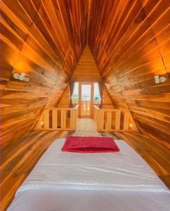 CALLA HOMESTAY DIENG في Diyeng: سرير كبير في غرفة خشبية مع نافذة