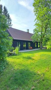 Kiigemäe maamaja : منزل أسود مع ساحة عشبية أمامه