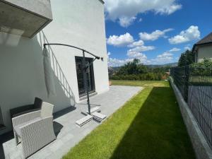 a patio with grass and white chairs on the side of a house at V.I.P Appartement in Böttstein