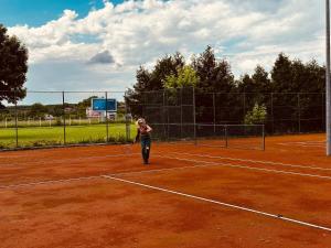 a woman standing on a tennis court holding a racket at Hotel Ada in Bihać