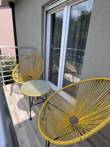 2 sedie gialle e un tavolo sul balcone di Apartmani Vivami a Budua