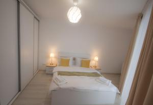 biała sypialnia z 2 łóżkami i 2 lampami w obiekcie Vivo Residence w mieście Baia Mare