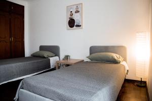 two twin beds in a room with a table at Cozy Room in Cascais City with Full Kitchen 5 minutes from the beach in Cascais