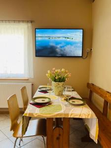 a dining room table with a television on the wall at Apartament u Ani 1 in Dźwirzyno