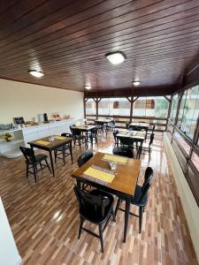 een restaurant met houten tafels, stoelen en ramen bij Pousada Recanto de Ponta Negra in Natal