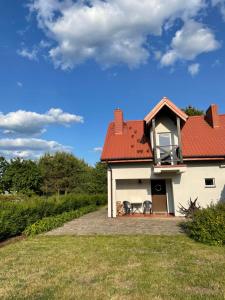 a white house with a red roof with two chairs at Domek nad Śniardwami in Suchy Róg