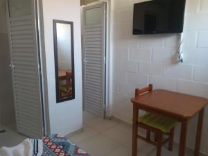 Cette petite chambre comprend une table et une télévision. dans l'établissement Quarto Aconchegante, à São Bento do Sapucaí